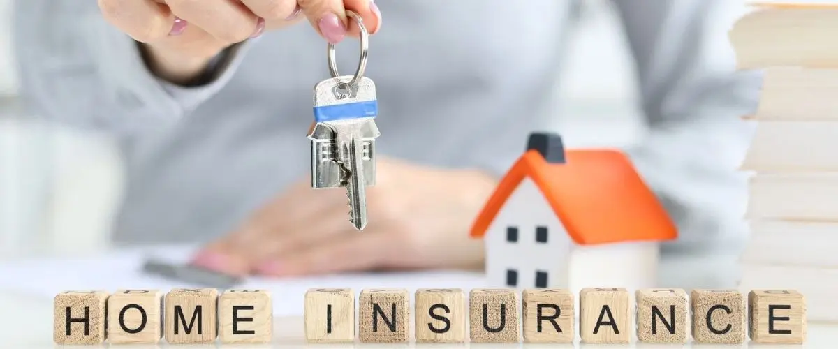 Keys held above wooden blocks spelling home insurance – represents secure property investment in Türkiye.