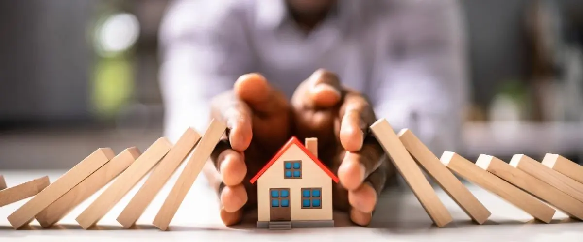 Protecting a house from risks with hands – visualizing the purpose of property insurance in Türkiye.